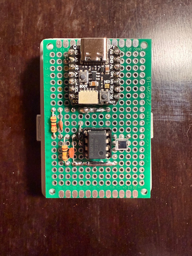 A perfboard with an Adafruit QT Py RP2040 at the top and a TLC271 op-amp next to a BPW34 photodiode at the bottom.