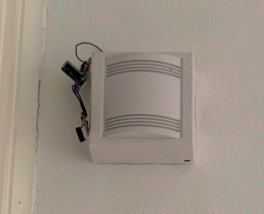 The sender board hanging out of a small hole in the gong's housing, wired into the bell, with the bulky capacitor sitting outside the enclosure.